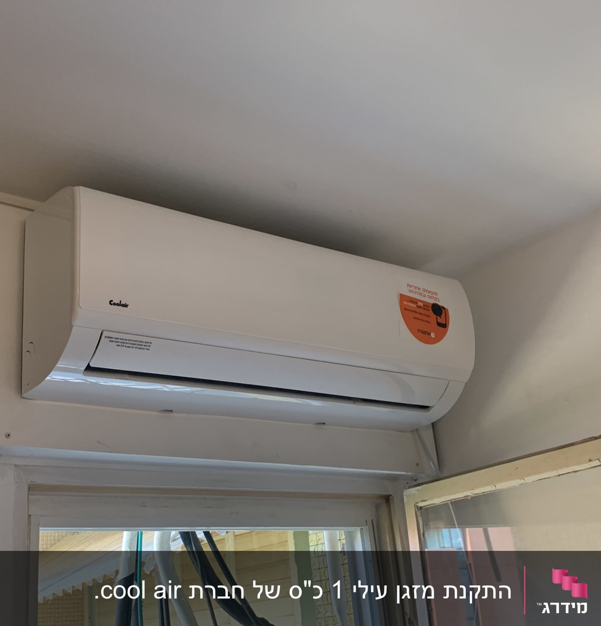 מזגן לבן מותקן על קיר מעל חלון